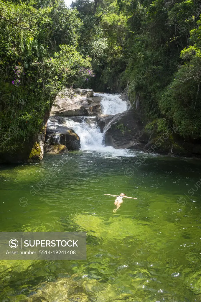 Beautiful view to woman swimming on green pool on rainforest waterfall