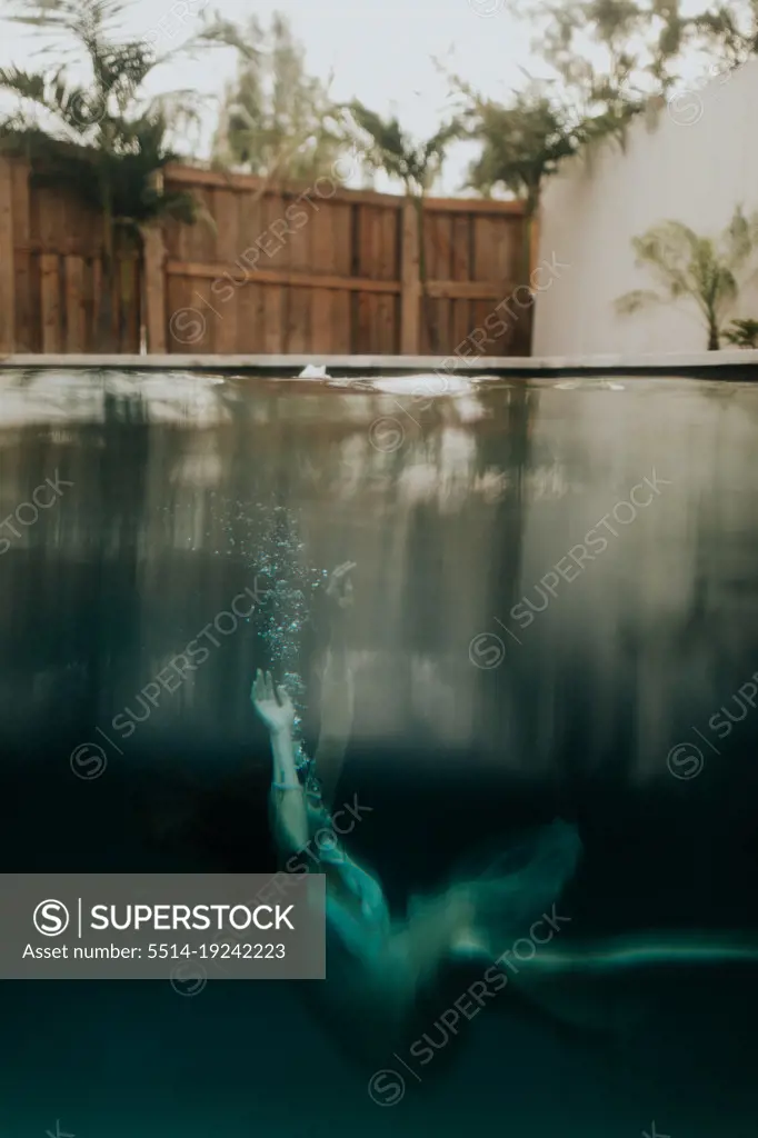 woman sinking in pool wearing a dress with bubbles