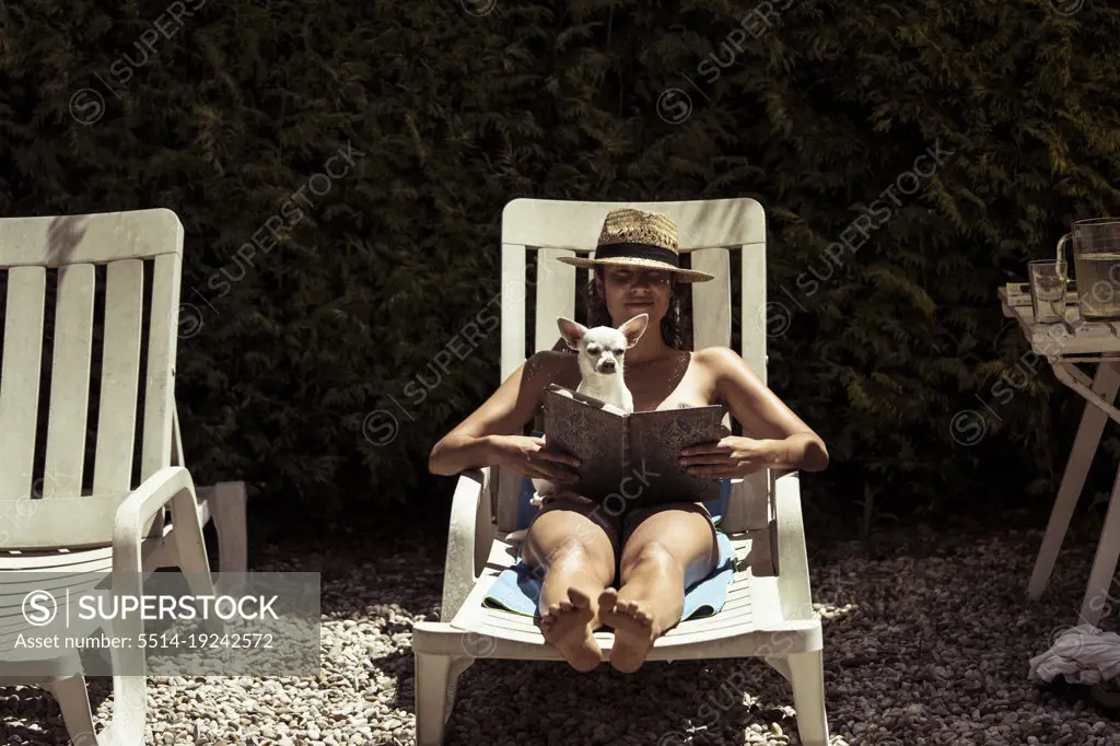 Lounging woman with small dog read in summer heat