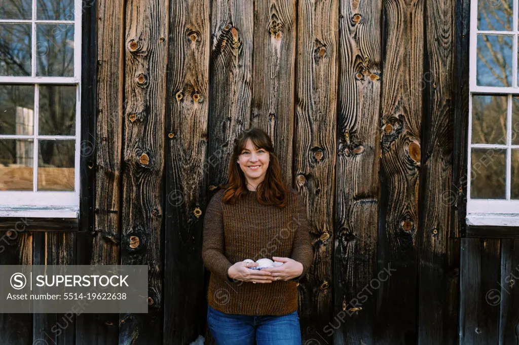 woman standing in front of her barn with goose eggs