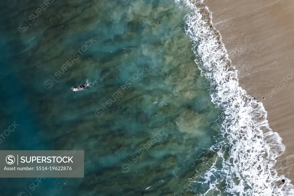 Male surfer paddles on board on Oahu, Hawaii