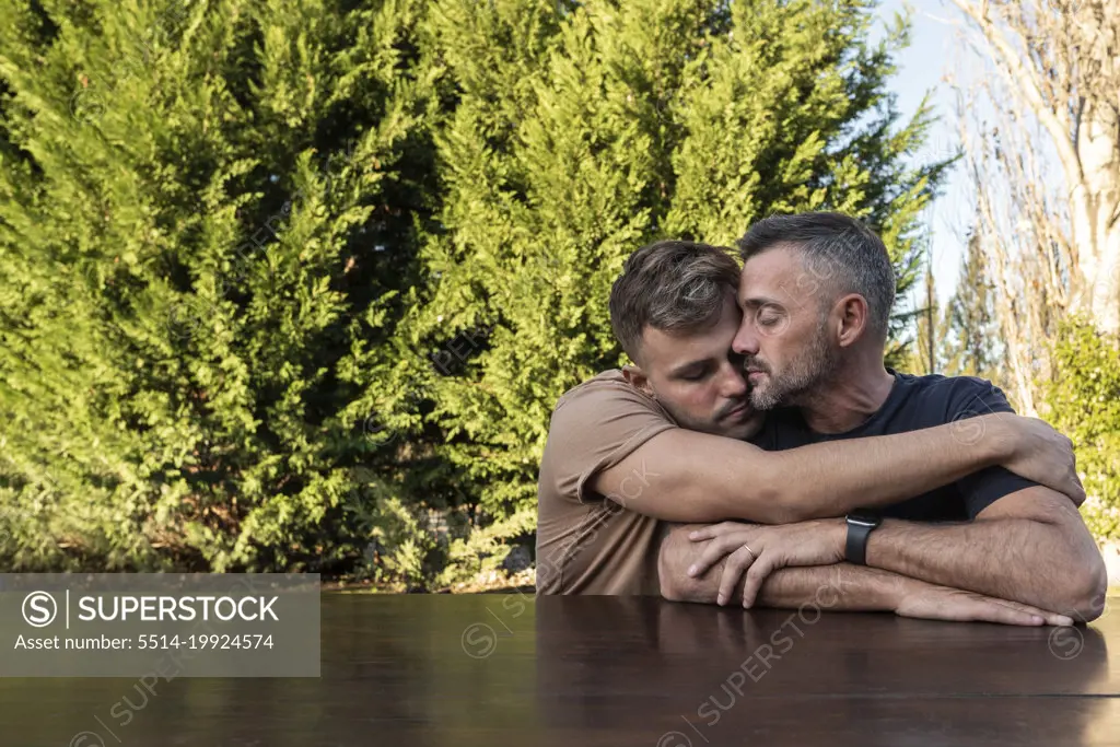 A young man hugging his husband. Both with eyes closed. copyspace