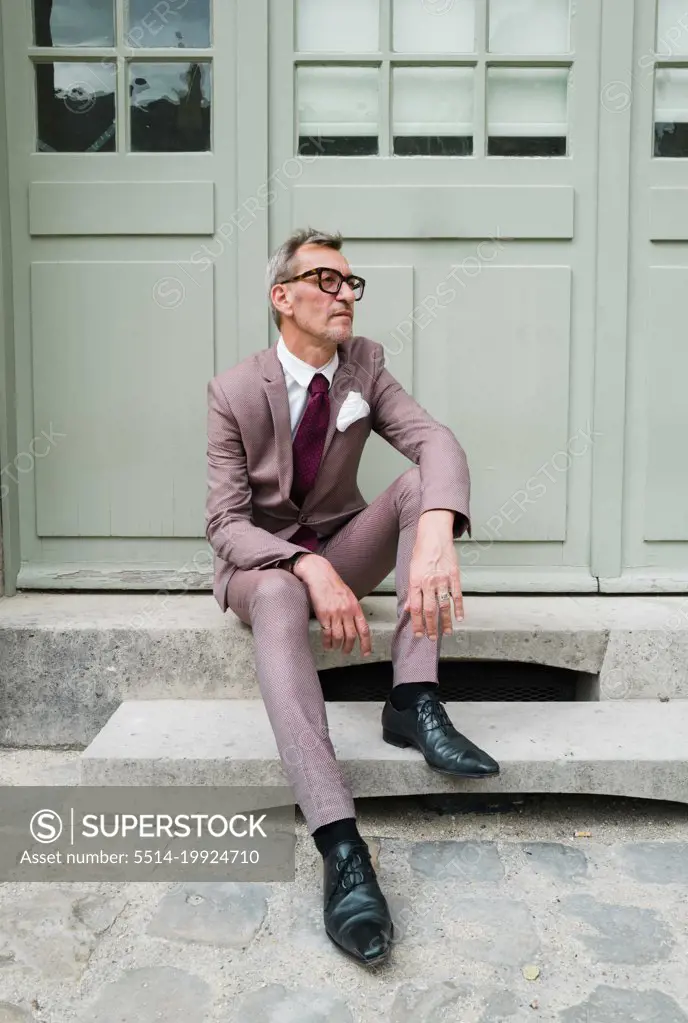 Portrait of the man in a suit sitting down in the doorway