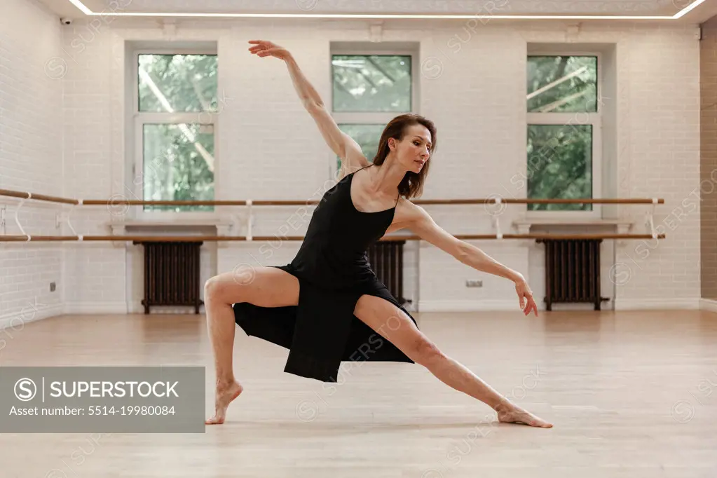 Beautiful  woman dancing in black dress in the hall