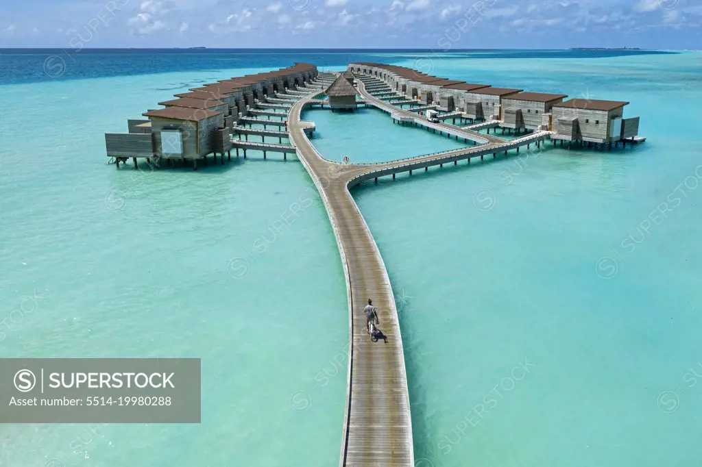 Aerial view of young man riding by bicycle on jetty in the sea