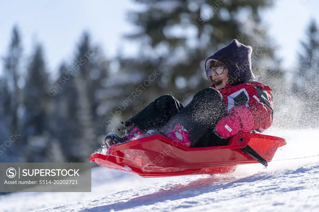 young girl playing with a bobsled in winter