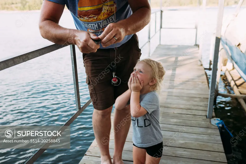 Dad getting fish off hook for excited young girl