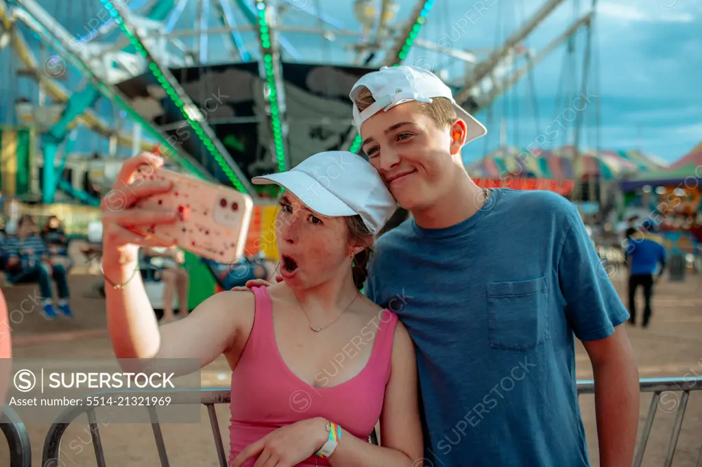 Goofy teens taking a photo in front of ride at carnival