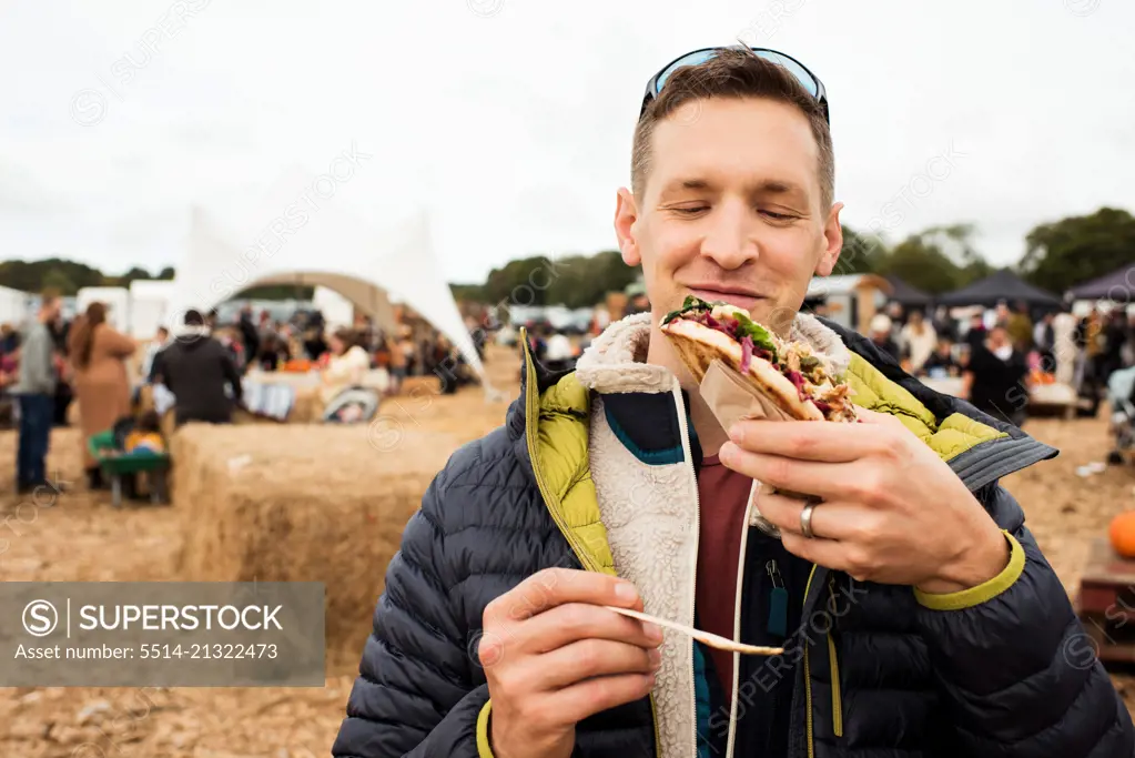 man happily eating delicious street food at a festival