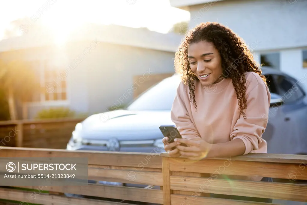 Smiling woman text messaging while leaning on railing