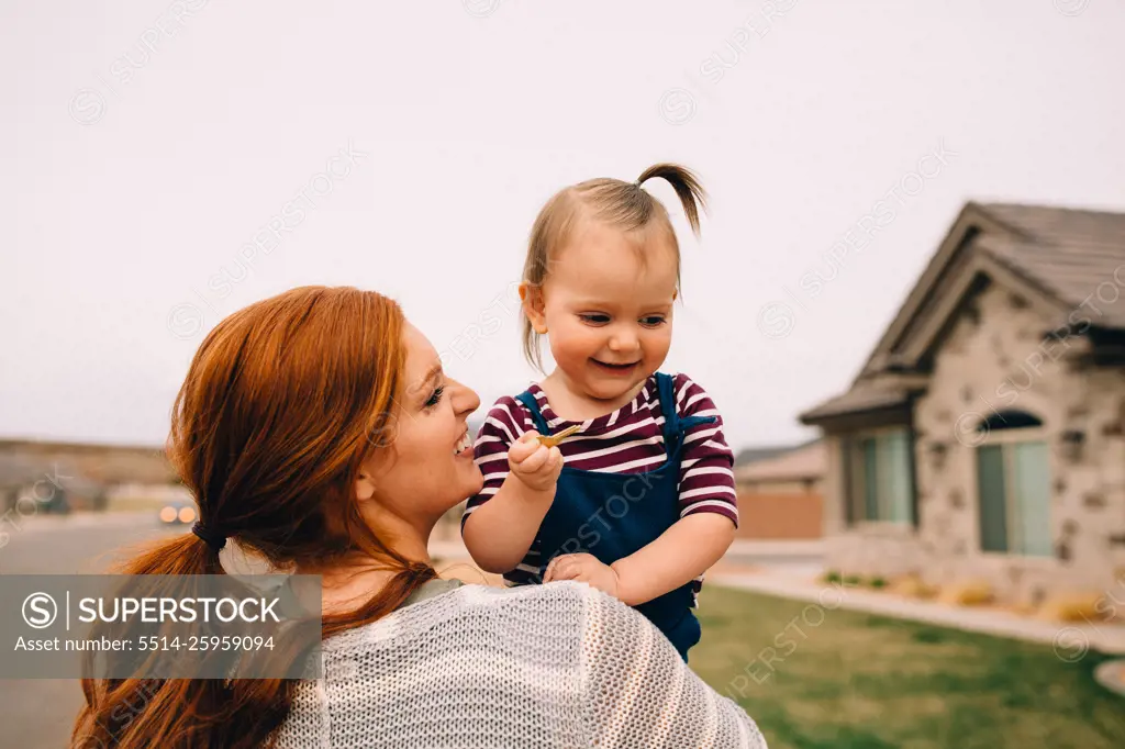 Playful mom holding baby outside holding house keys