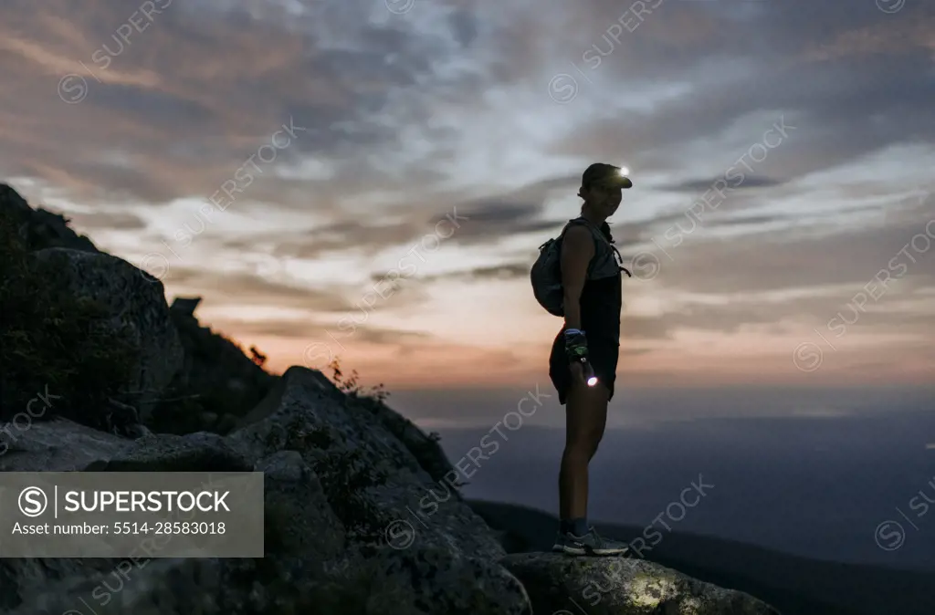 female hiker with headlamp hikes Katahdin at sunrise