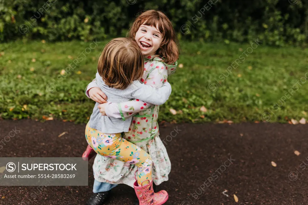 Sisters laugh and play along walking trail on a cloudy fall day