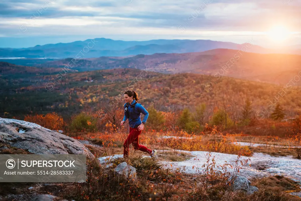 Woman trail running in mountains with foliage in autumn