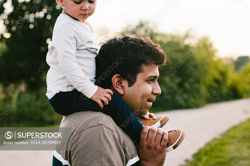 Dad carries son on shoulders during outdoor adventure and hike