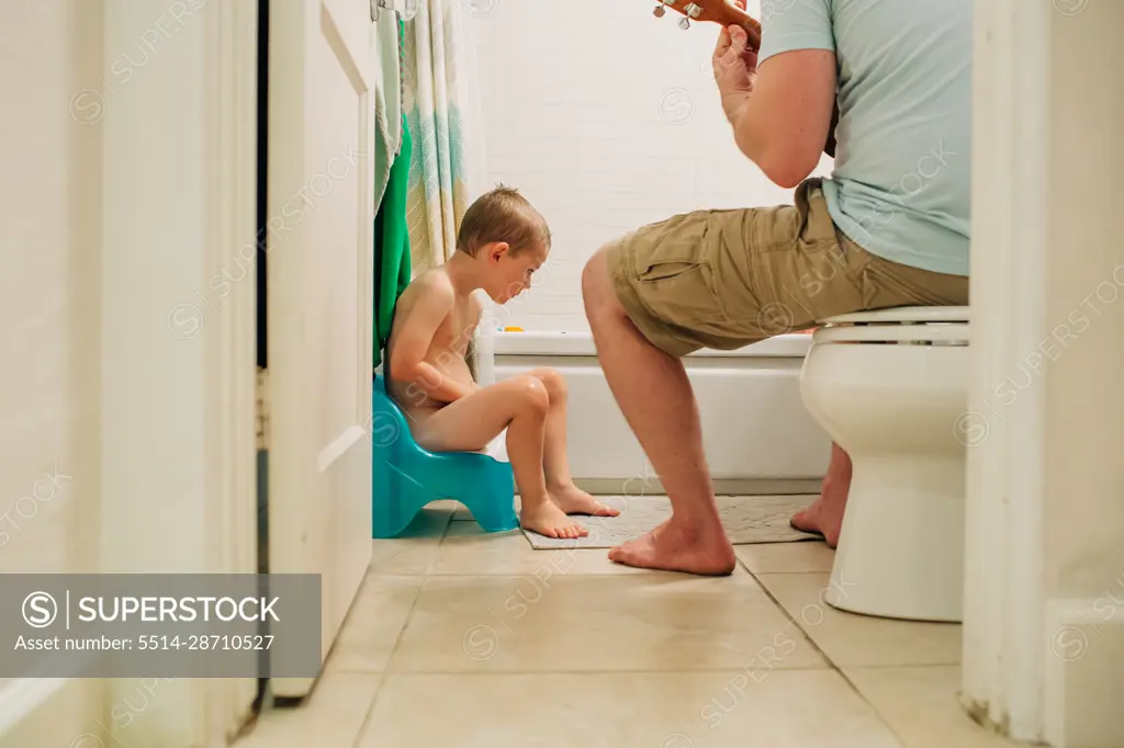 Four year old boy learning to potty train with dad helping