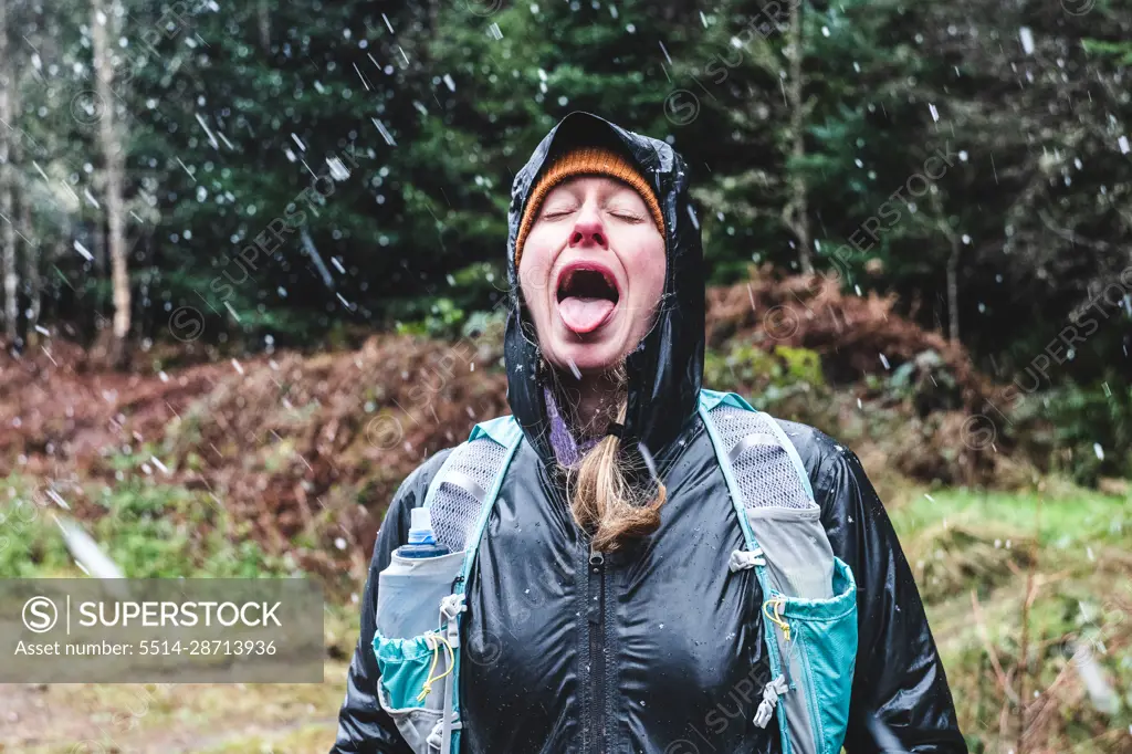 Woman with mouth open catching snow flakes on tongue