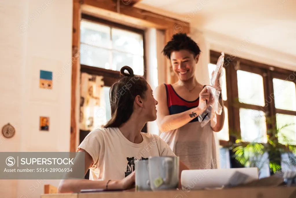 Queer couple laugh and smile together preparing to dye hair