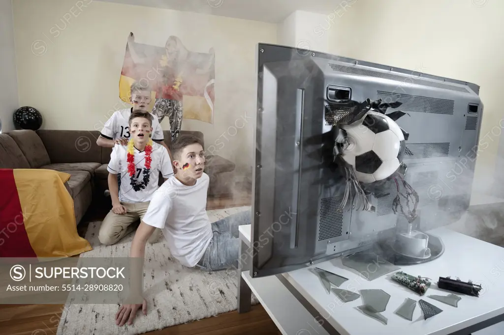 Teenage soccer fans in living room with ball demolishing TV