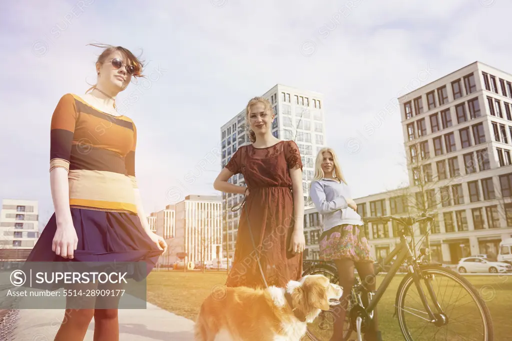 Three friends in a playground with dog, Munich, Bavaria, Germany