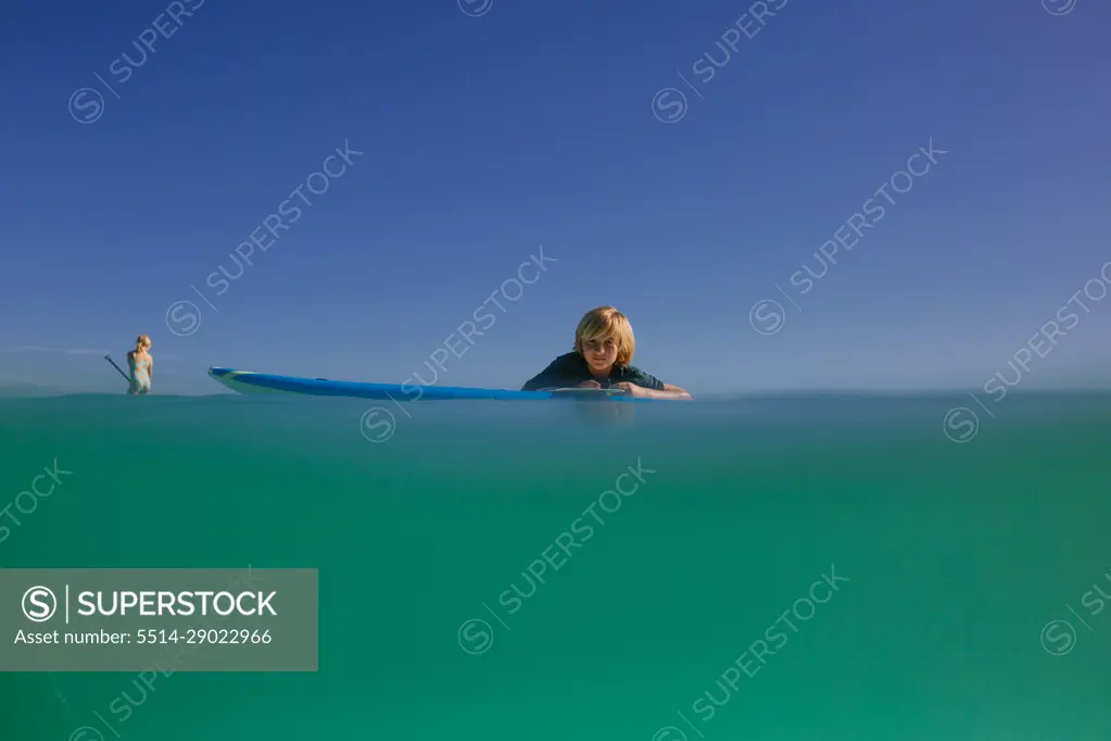 Siblings paddleboard in turquoise waters of Hawaii