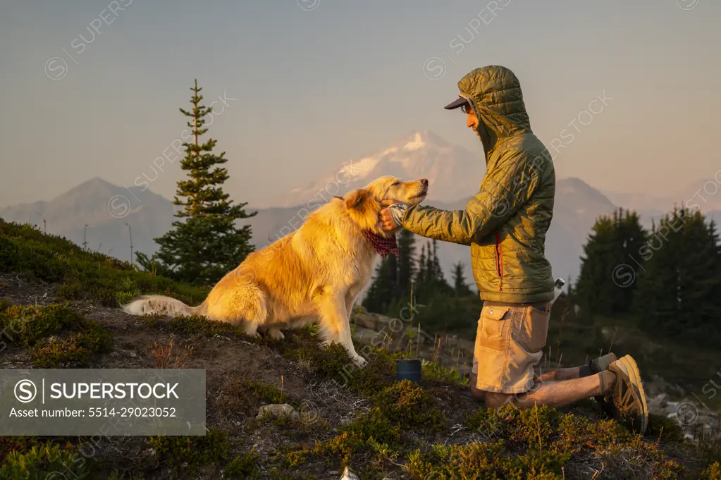 Dog getting pets and scratches as the sun sets in the alpine