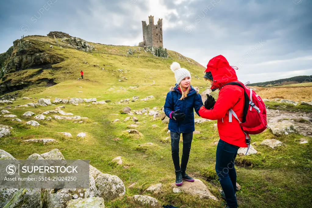 Daughter Looking at Mother on Winter Walk Overlooked by Ruin