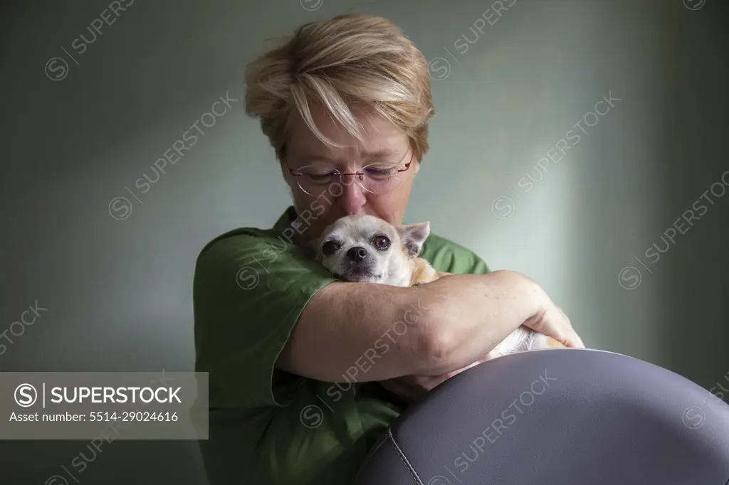 A doctor kissing her chihuahua on the head