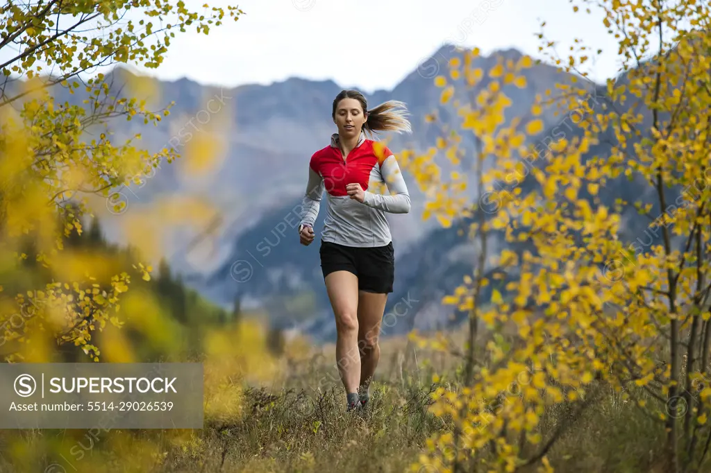 Young woman running in forest during autumn