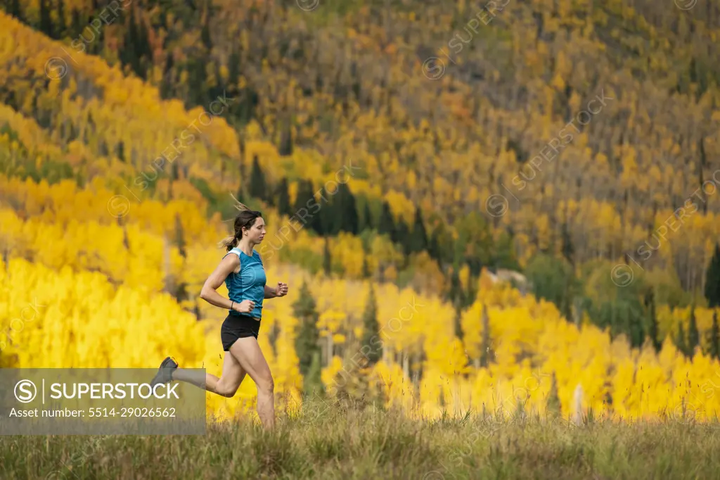 Young woman running on field during autumn