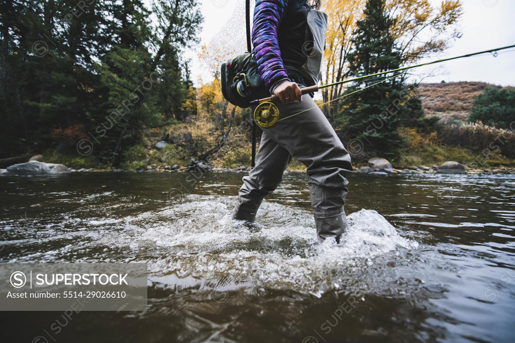 Midsection of woman fly fishing at Roaring Fork River - SuperStock