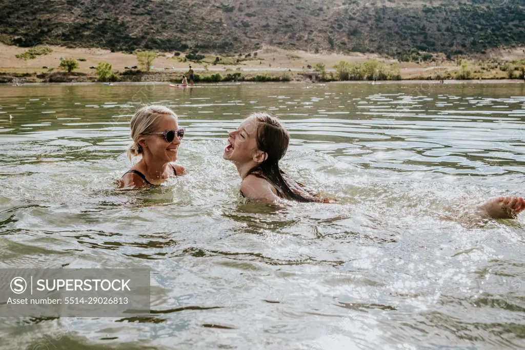 Happy mother and daughter swimming in a lake on a summer day