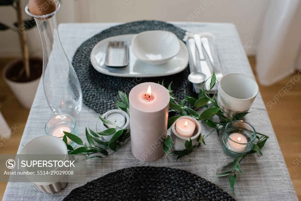 large candle on a romantic dinner table set up at home for two 