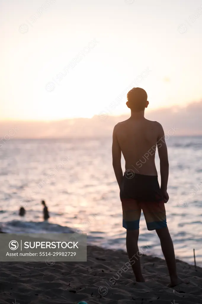 teenage boy watching the sunset on the north shore of oahu