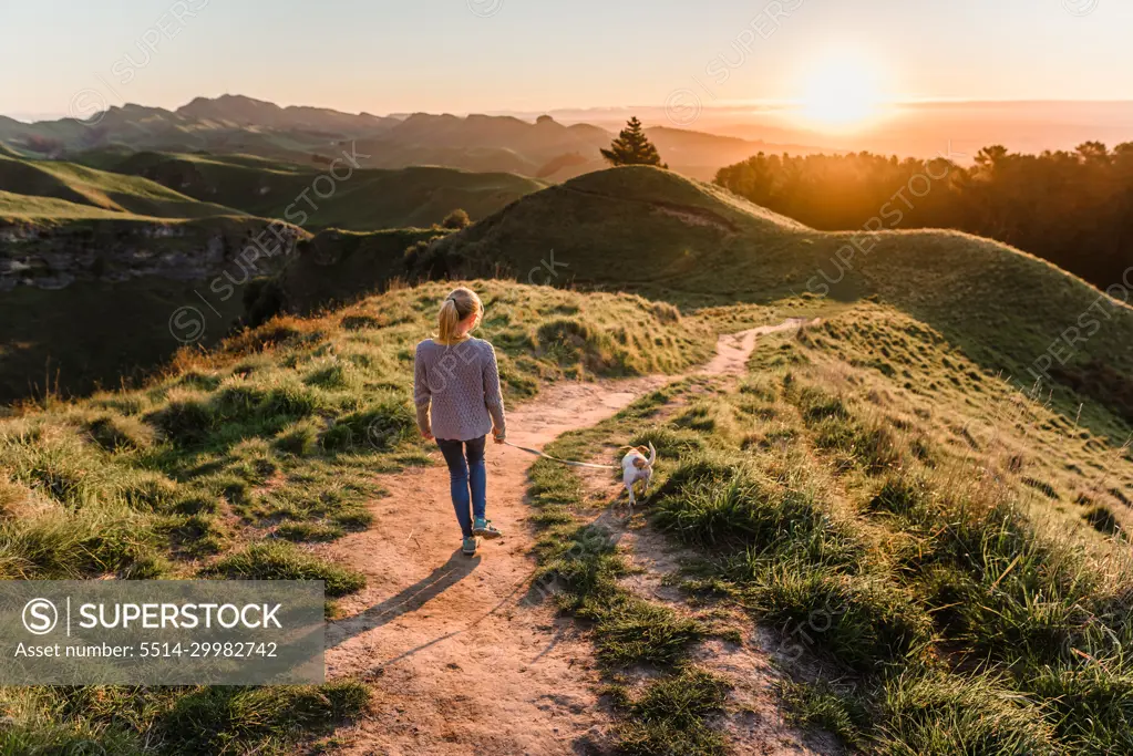 Preteen girl walking dog at sunset on Te Mata Peak in New Zealand