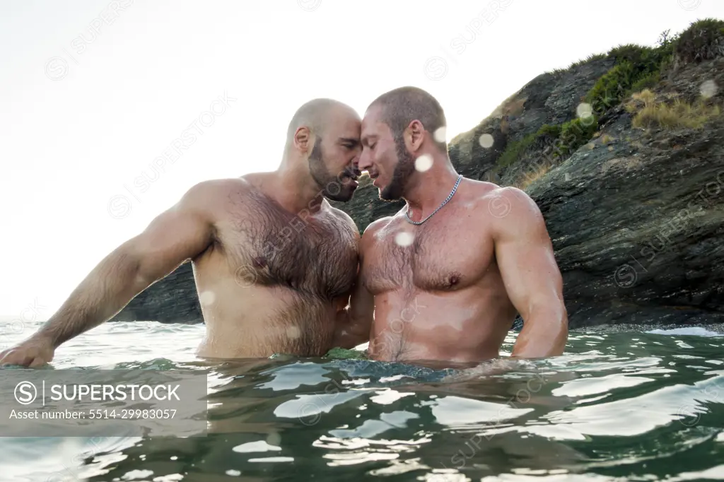 Lgbt pride concept. Male gay couple in affectionate pose in the sea.