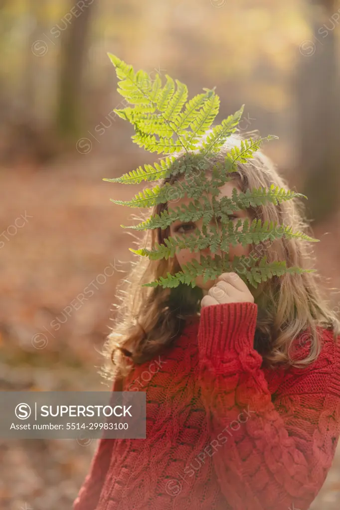 portrait of a teenage girl with a fern leaf in the autumn forest