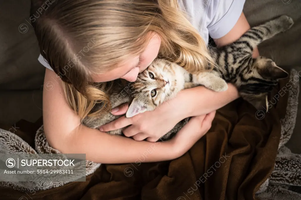 Young Girl Looking Down Holding Kittens on Brown Blanket