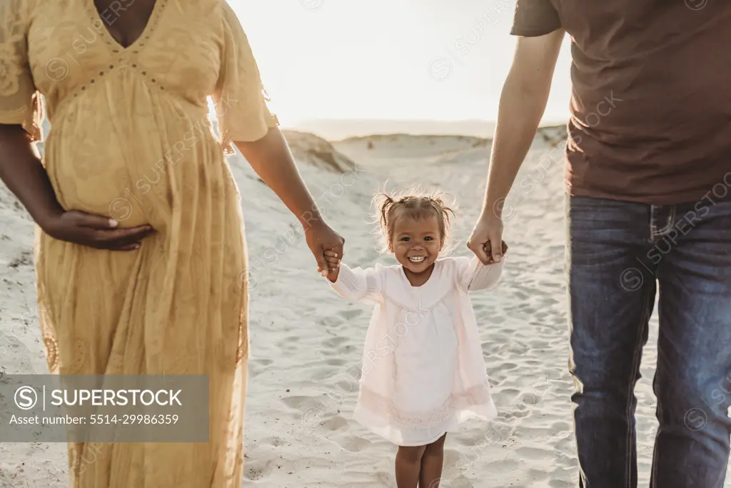 Young family of three walking and playing at beach