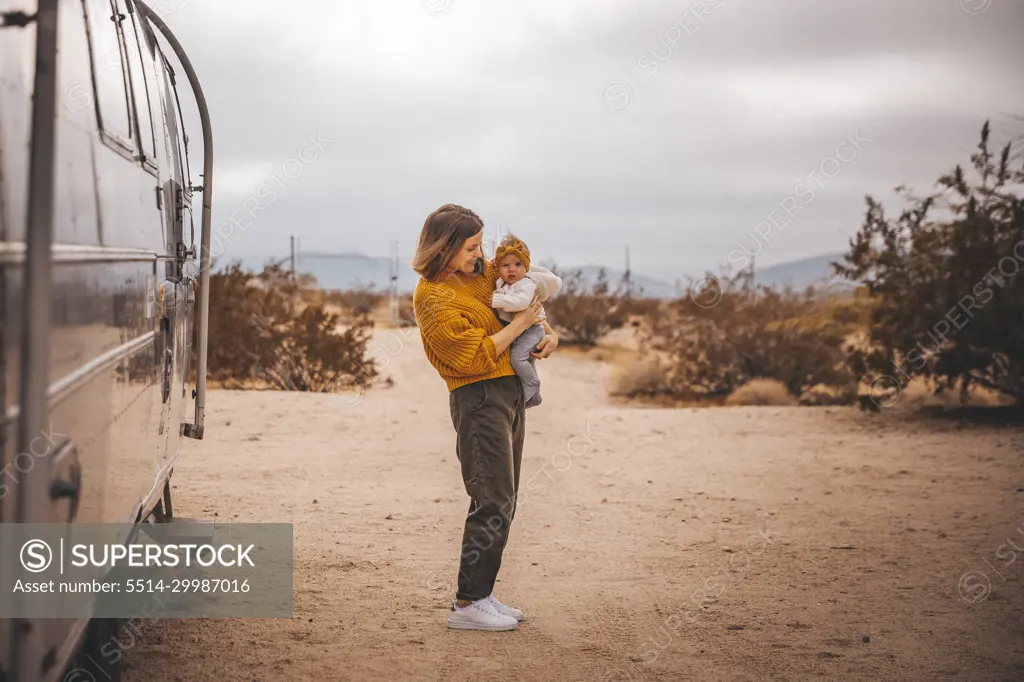 A woman with a baby is near an RV trailer, Joshua Tree, California