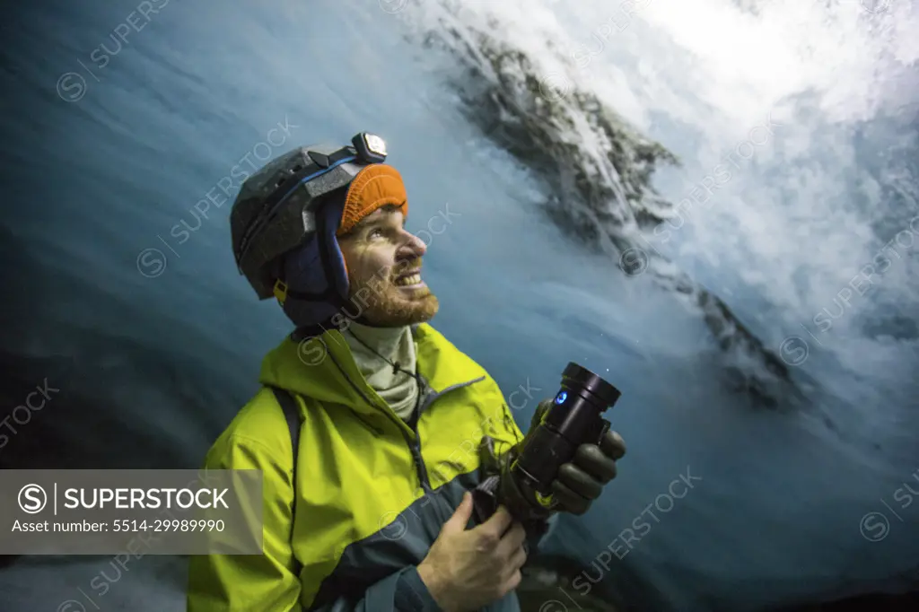 Explorer shines light on glacier above, illuminating the blue colours