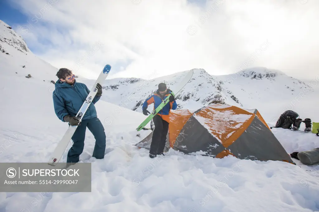 Two skiers use their skis as air guitars, jam session at basecamp