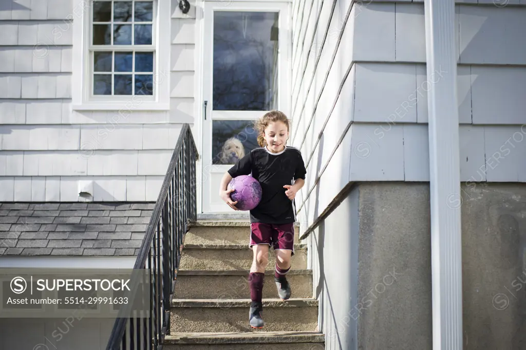 Girl running down stairs with soccer ball