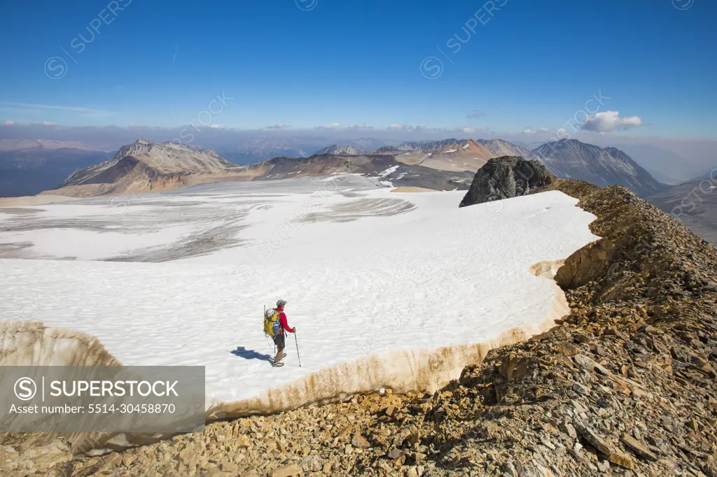 high angle of backpacker hiking across tip of huge glacier.