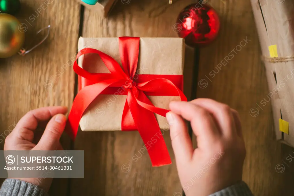 Woman wrapping christmas gifts on wooden background