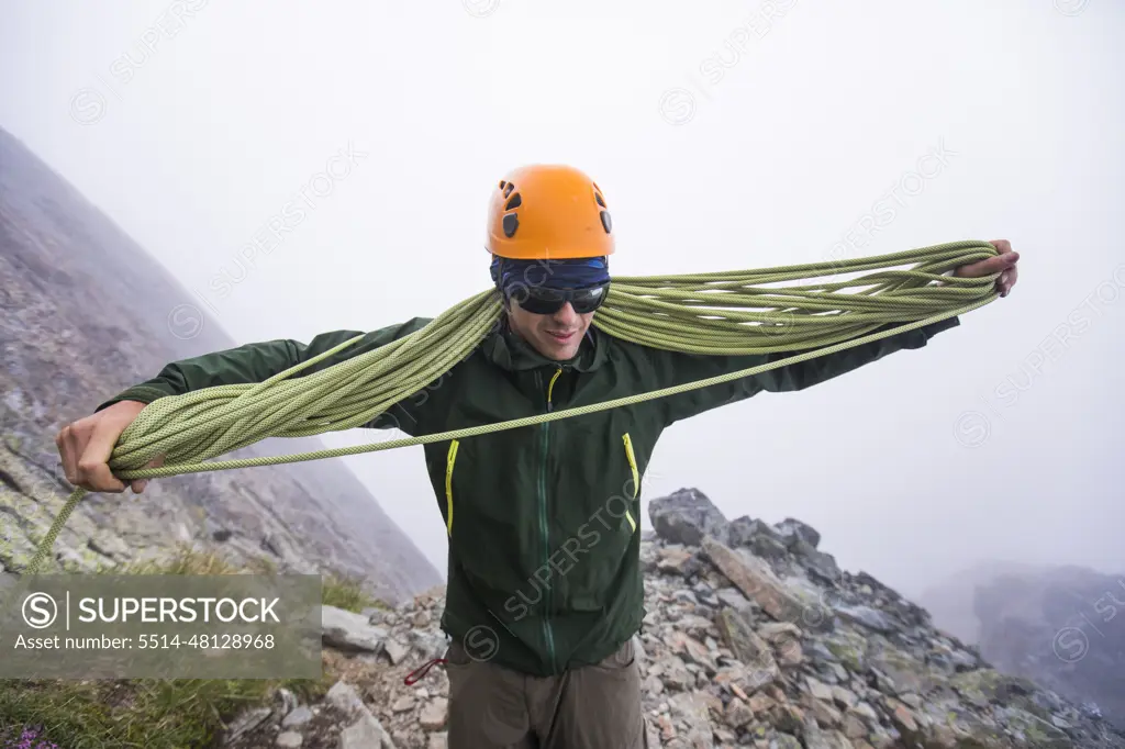 Climber coils climbing rope after rappel.