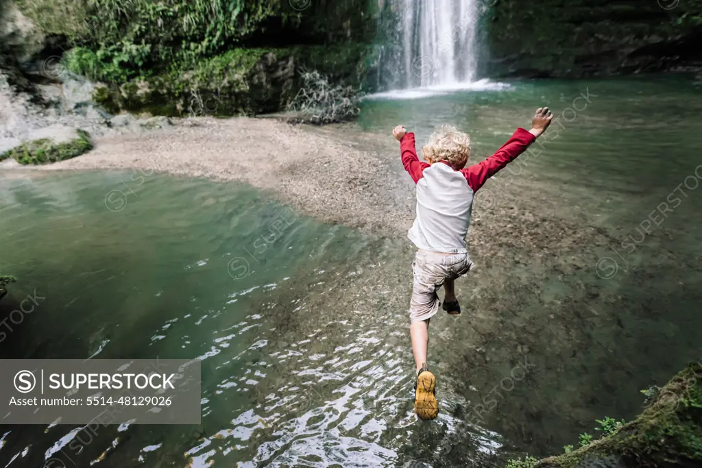 View from above of preschooler jumping into water in New Zealand