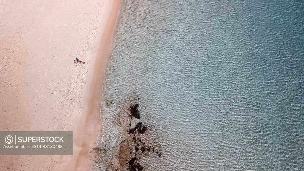 a woman alone on a beach with a clear blue water in Greece