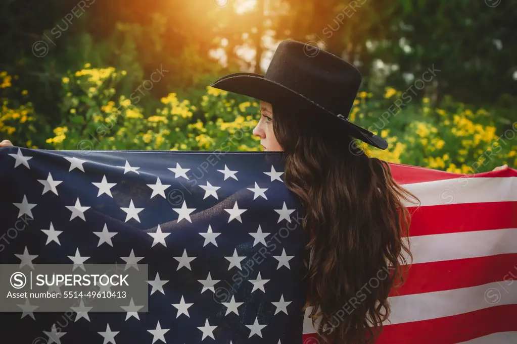 Young teen in cowboy hat holding American Flag