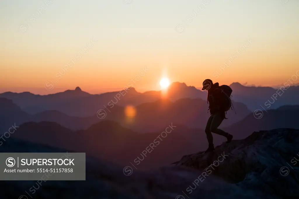 Silhouetted view of fit healthy woman running on mountain summit